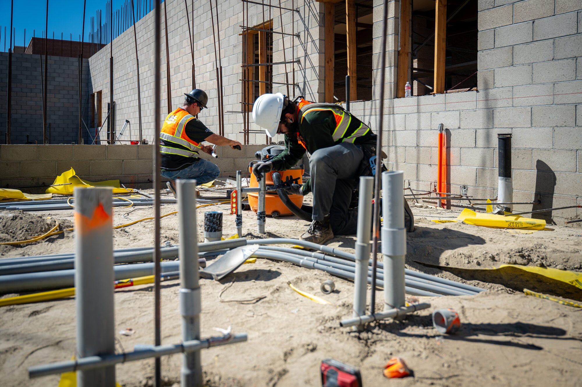 Electrician bending conduit at a block wall rough in