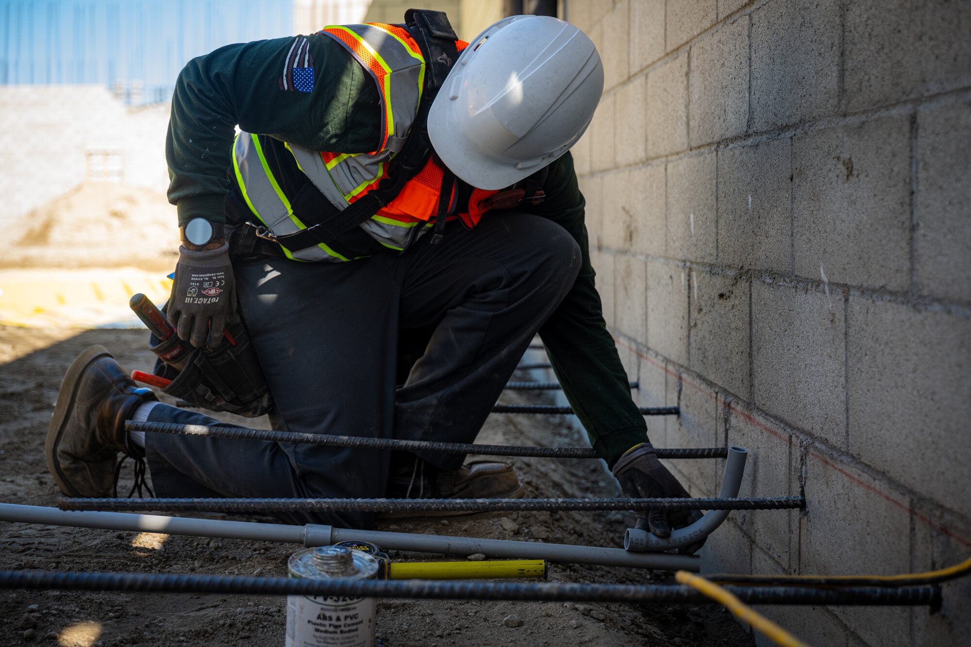 Electrician kneeling to set conduit before the pour