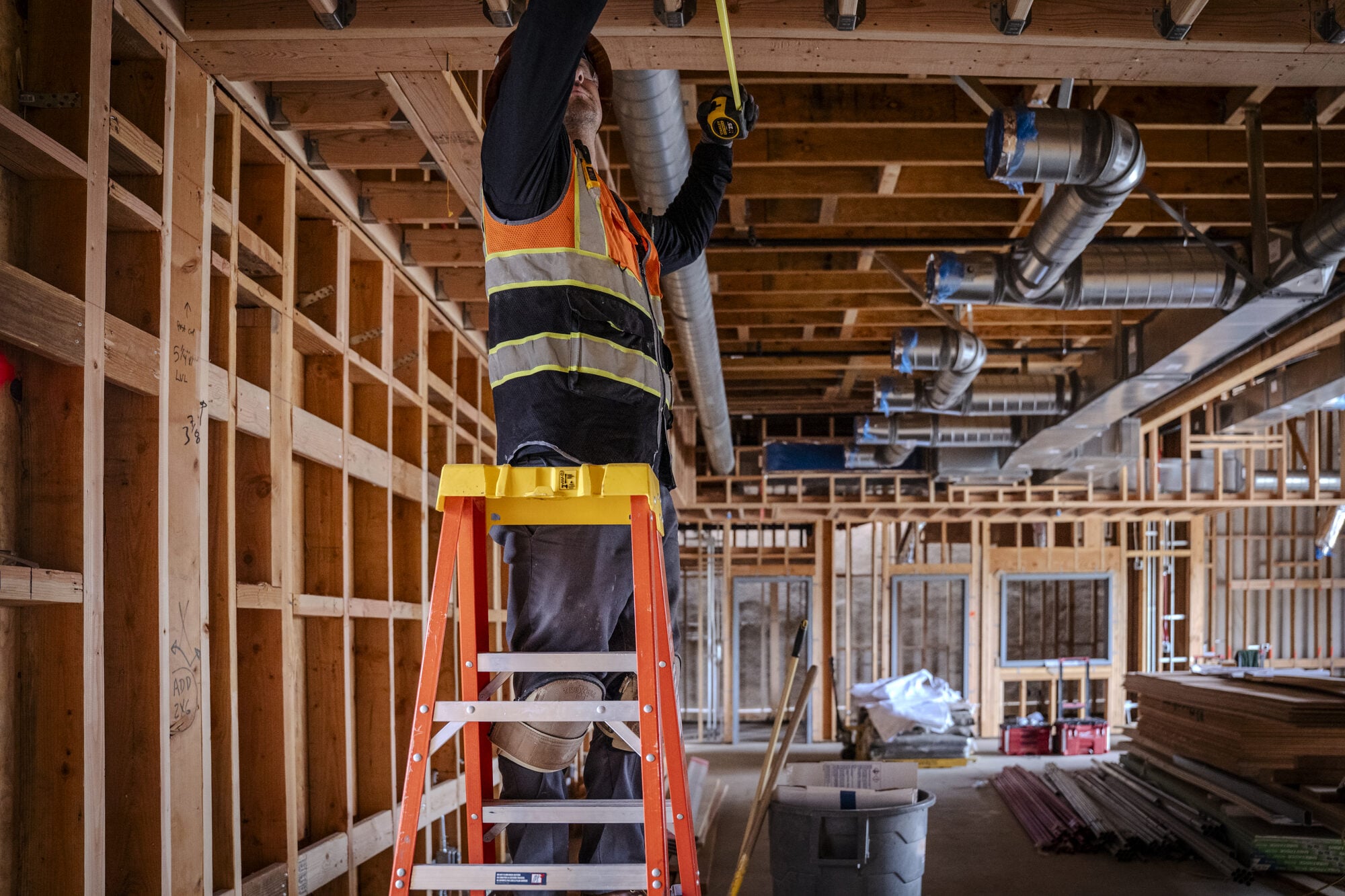 Electrician running overhead conduit from a ladder inside the Lakeside Middle School addition